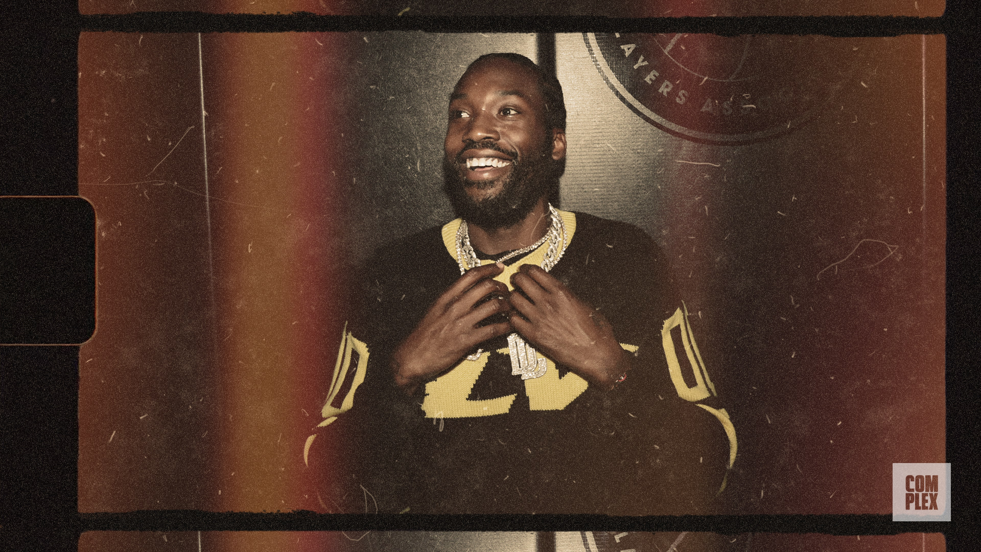 A man smiling, wearing a black and yellow jersey with the number 21, and a chain necklace. The image has a vintage filter.