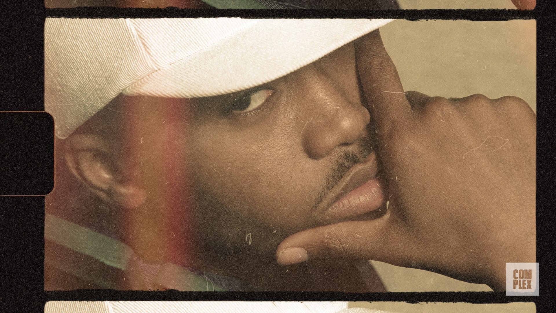 A close-up of a person wearing a white cap, looking at the camera with their hand near their face. The image has a vintage filter.