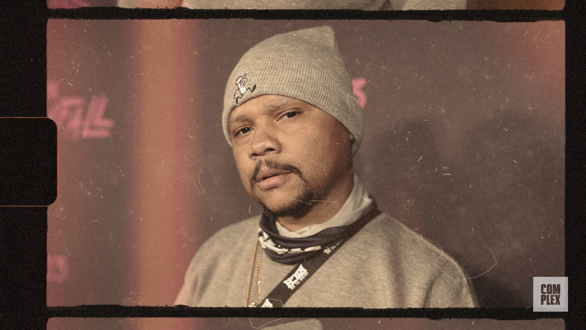 A man wearing a gray beanie and sweatshirt, standing against a backdrop with a vintage filter effect.