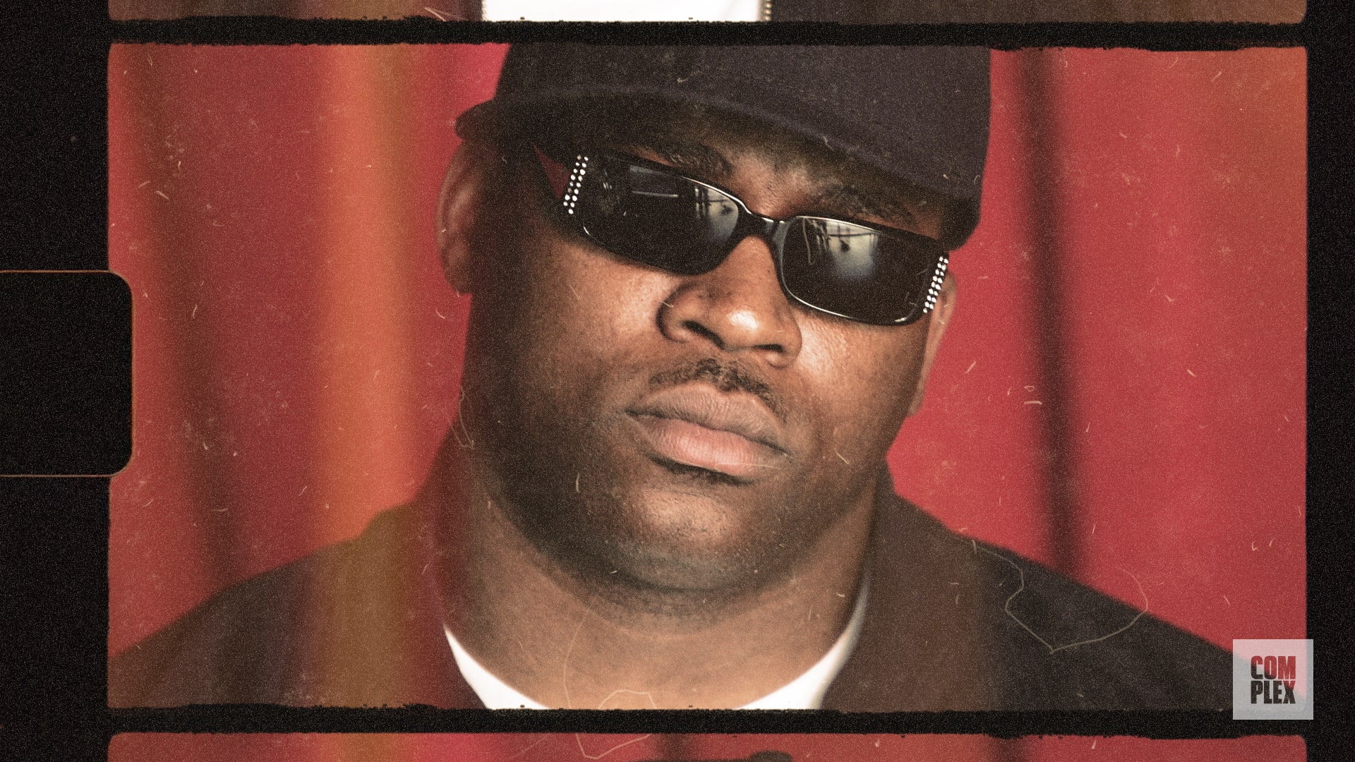 A person wearing sunglasses and a cap against a red background, with a vintage film effect.