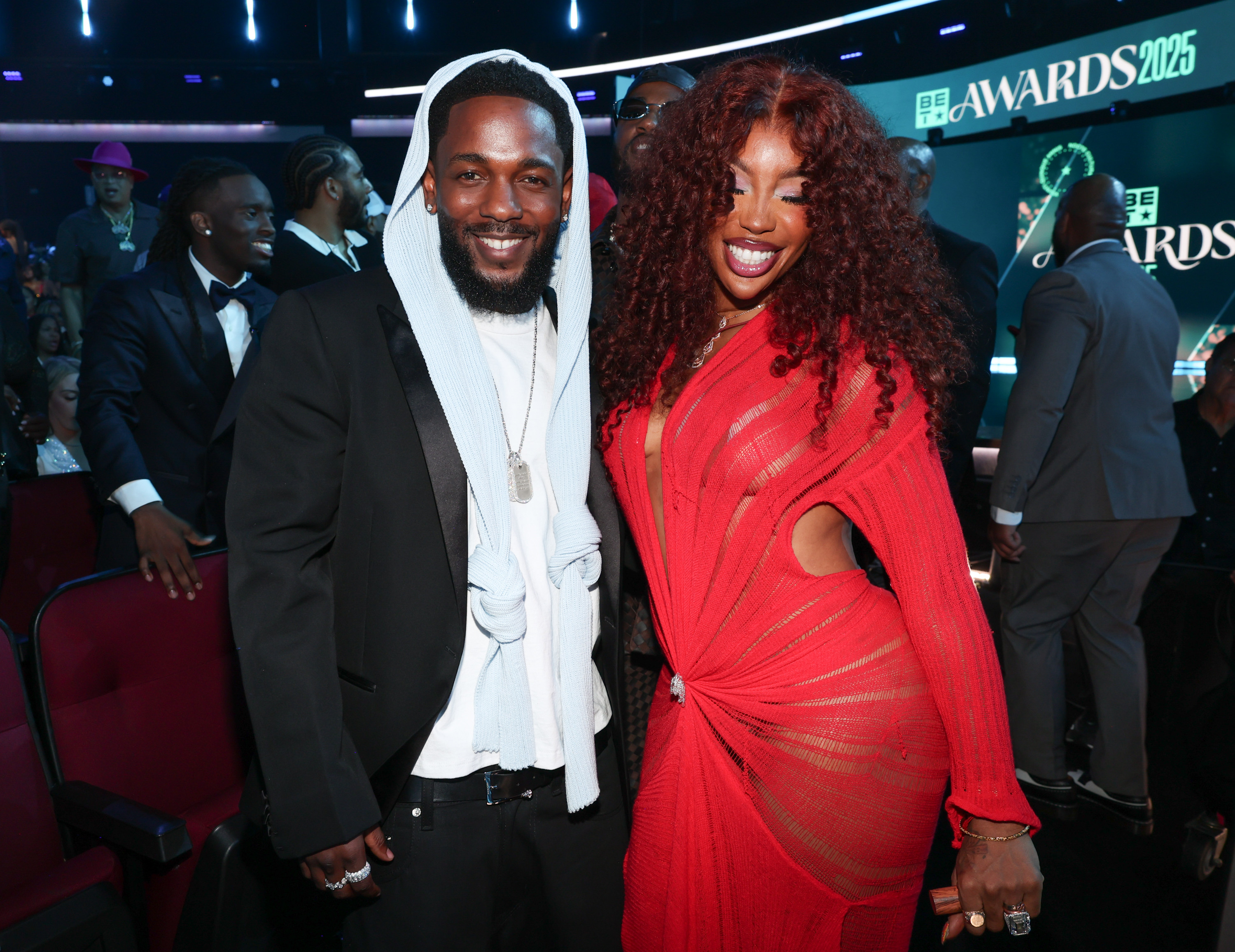 Kendrick Lamar in a black suit with a white hoodie and SZA in a red dress smile at the 2025 BET Awards. they are expected to win Grammys for 