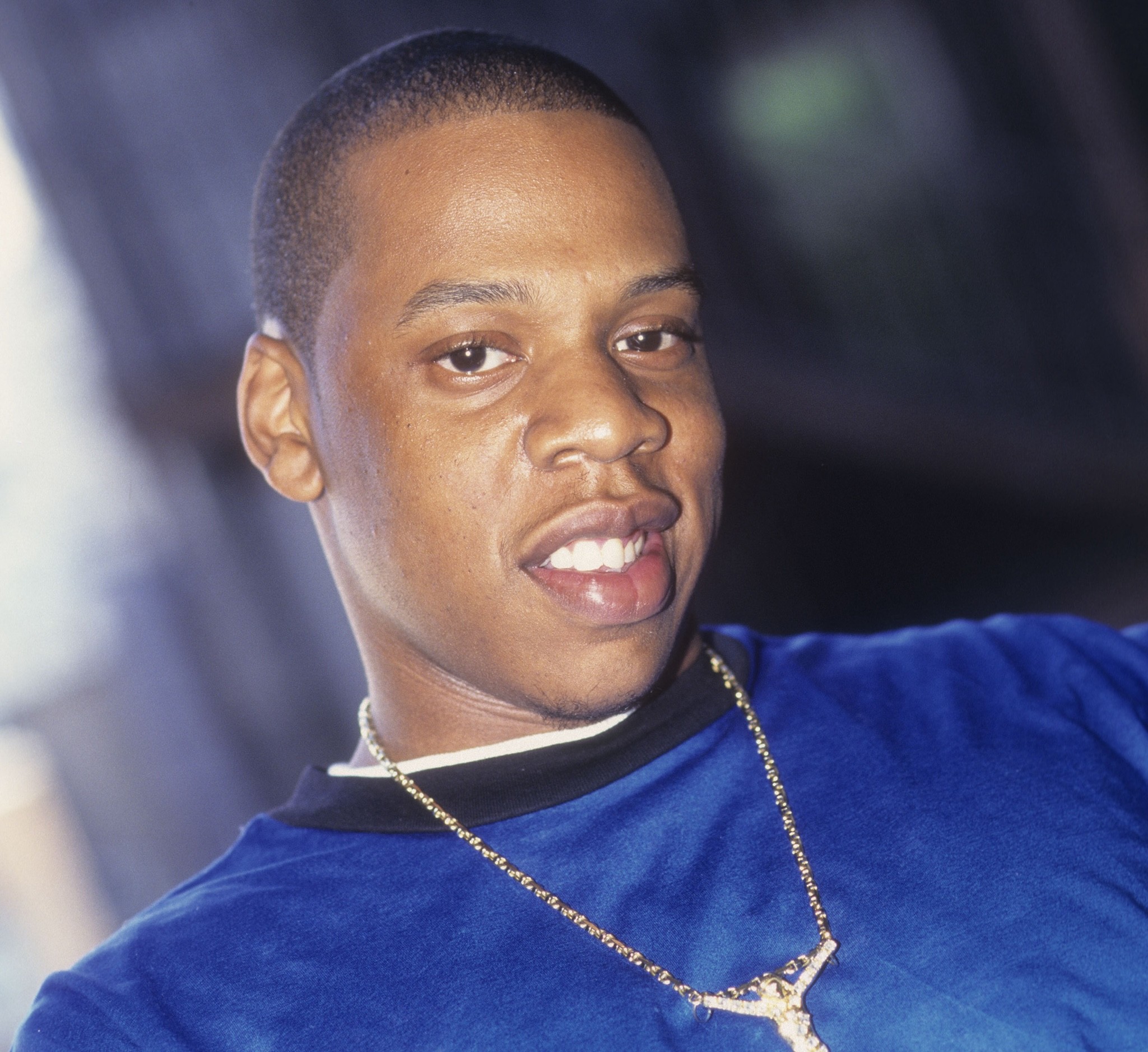 Jay-Z smiling, wearing a blue shirt and a gold chain. This was in the late '90s when he was releasing Reasonable Doubt. 